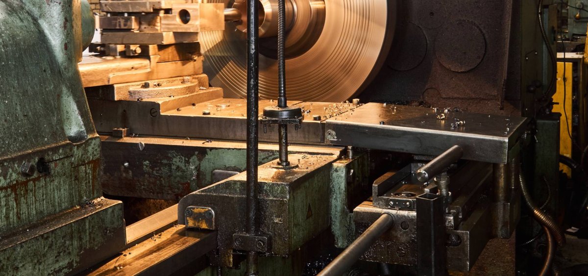 Torno industrial maquinando una pieza cilíndrica de gran escala en el taller